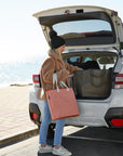 Woman carrying peach reusable bag to the boot of her car