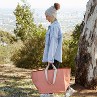 Woman walking carrying big Peach coloured reusable bag