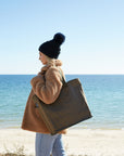 woman with a beanie at beach carrying large reusable bag over her shoulder