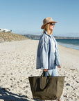 Woman at the beach carrying a big Khaki reusable bag
