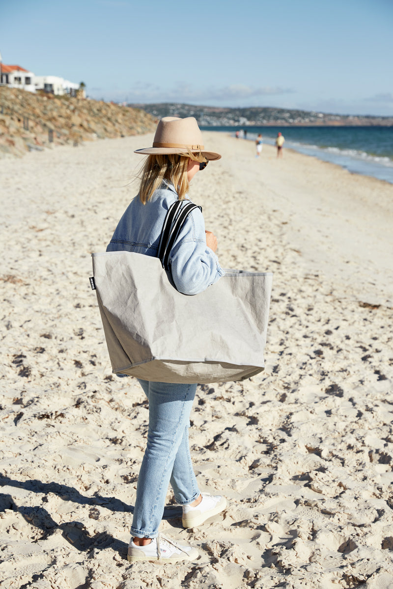 Woman at the beach carrying stone reusable bag
