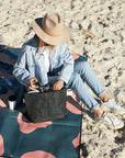 Woman on a beach sitting on colourful picnic blanket