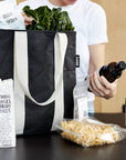 Woman unpacking contents from black recyclable grocery bag